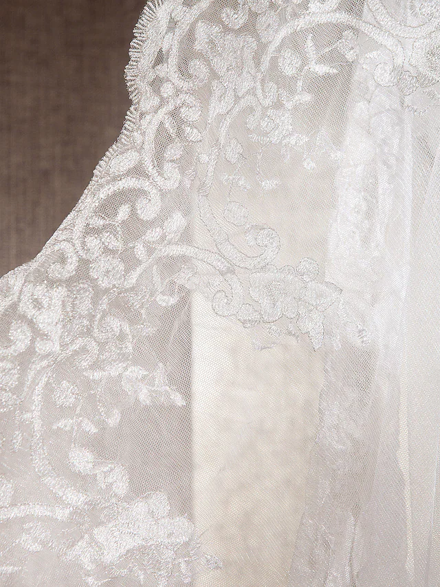 Bride posing in an elegant lace and tulle mermaid trumpet wedding dress.