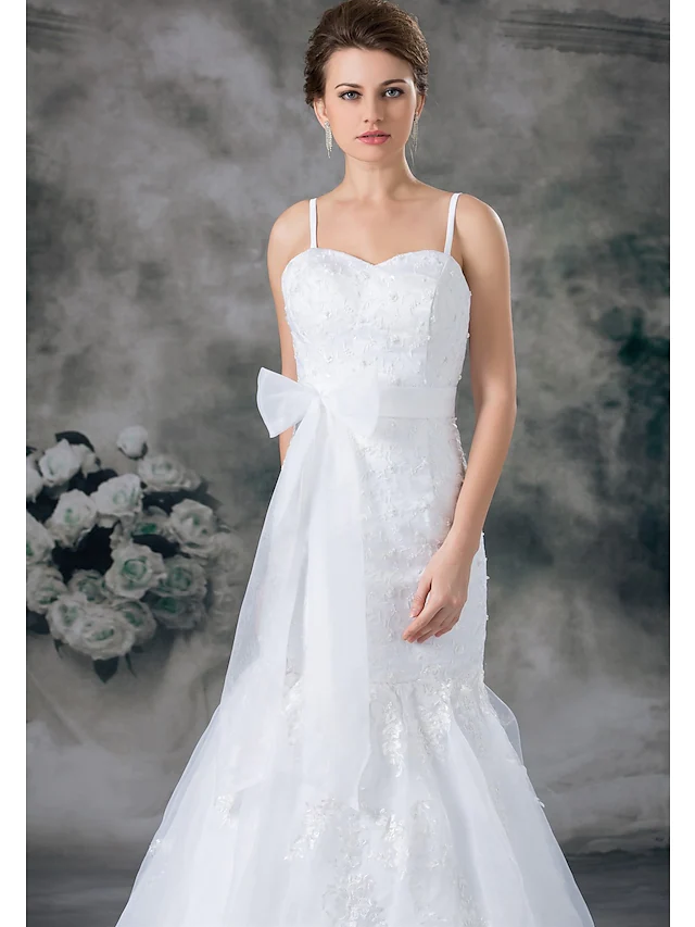 Side view of a bridal gown featuring spaghetti straps and lace embellishments.
