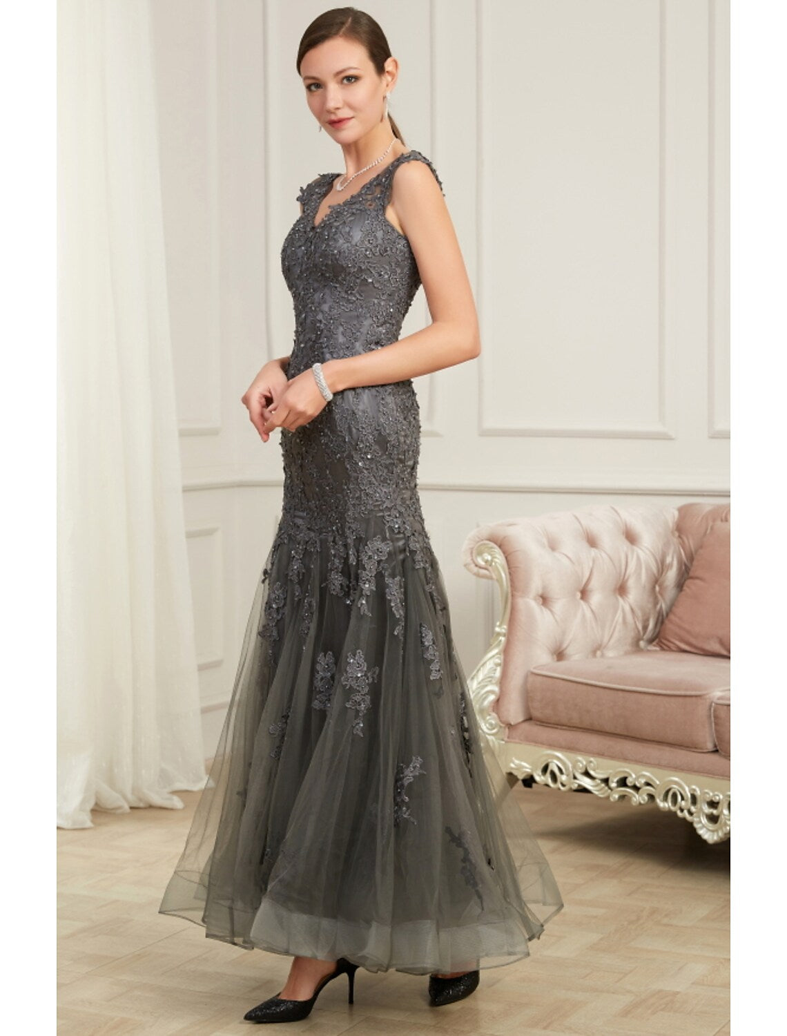 Woman posing in a sleeveless V-neck sequined evening dress.