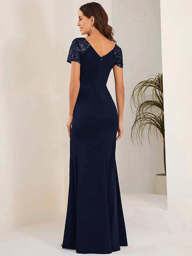 Full view of the woman posing gracefully in the crystal-embellished mermaid trumpet gown.