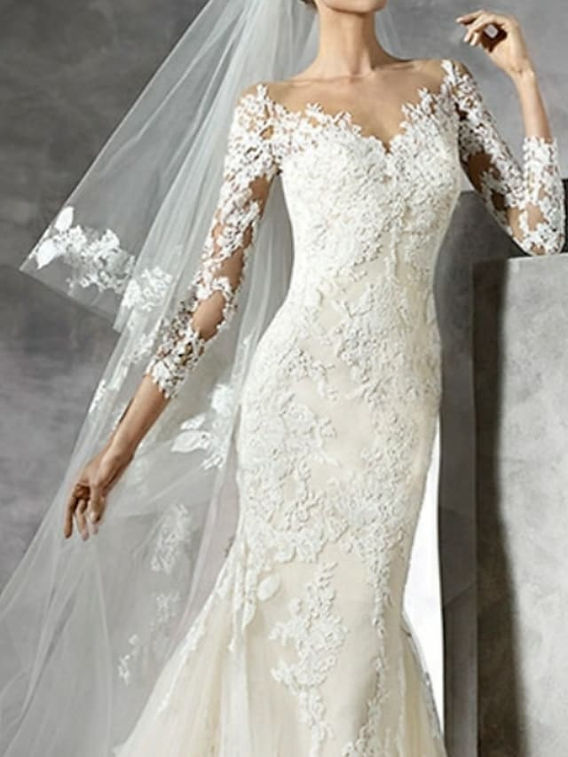 Full length view of a white V-neck wedding gown with delicate lace details.
