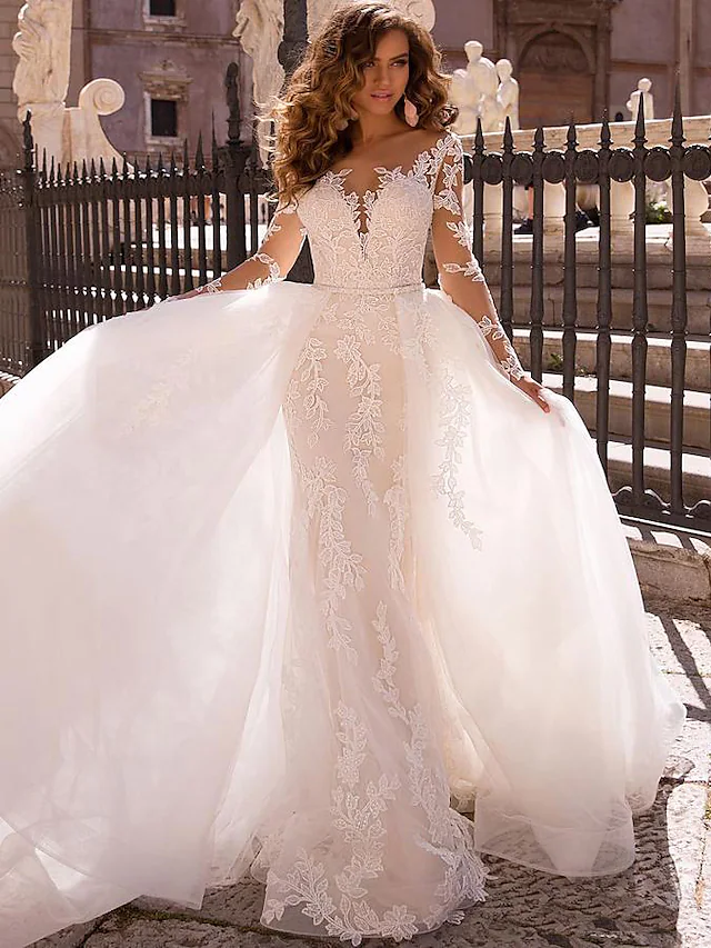 Bride in elegant mermaid V-neck lace wedding dress with detachable illusion sleeves and court train.