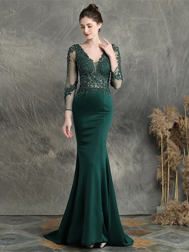 A woman modeling an elegant long sleeve V-neck mermaid prom dress with beading and appliques.