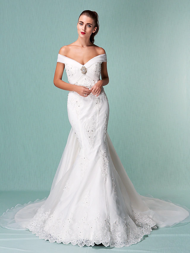 Back view of an off-shoulder organza wedding dress showing chapel train and beading.