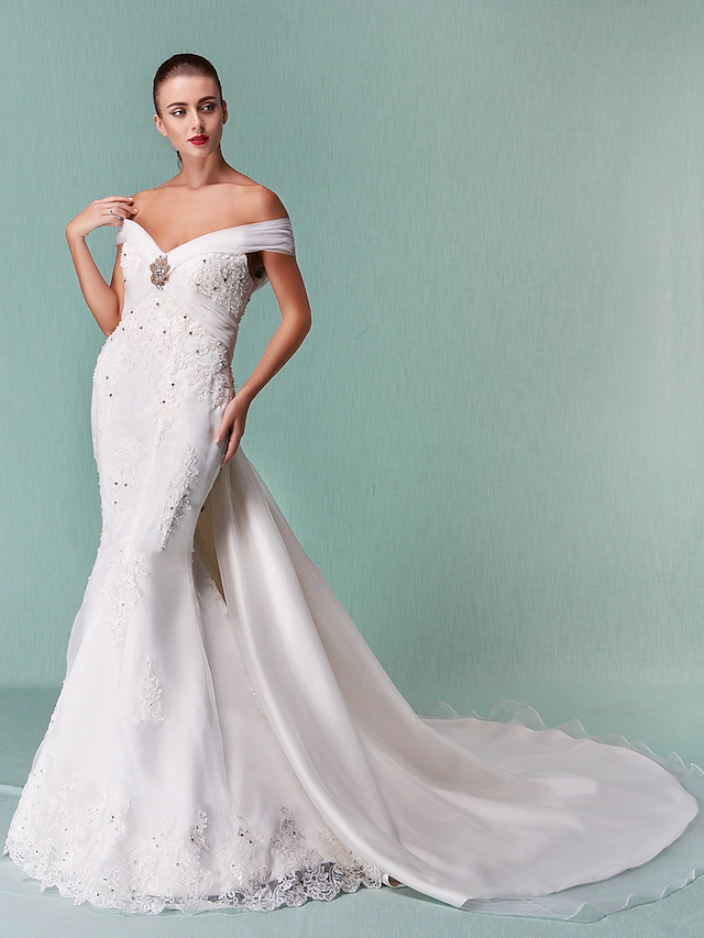 Full length view of an off-shoulder organza wedding dress with a flowing chapel train.