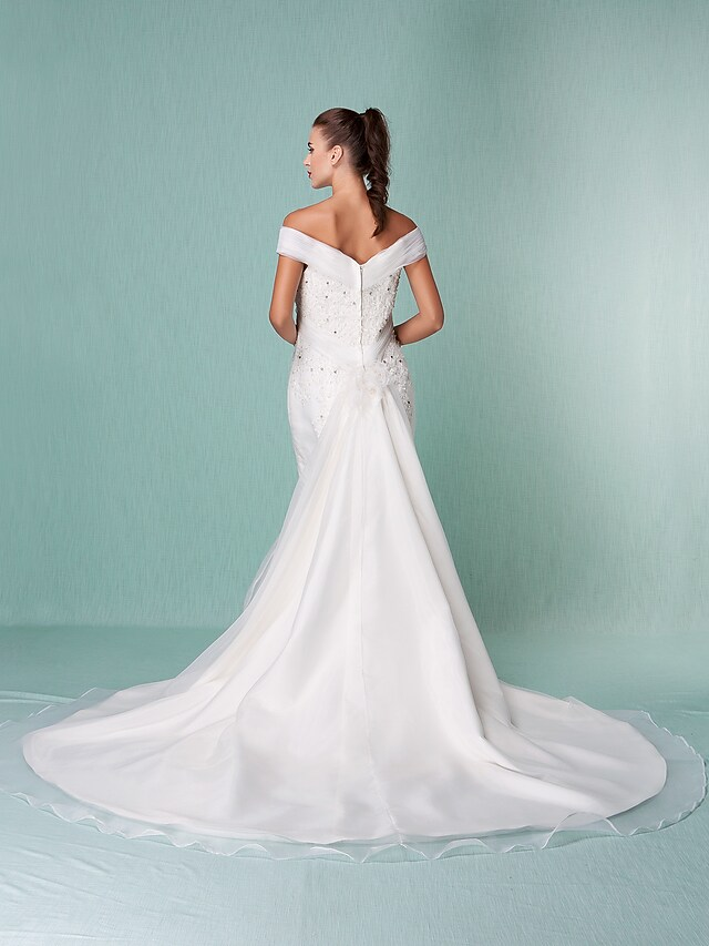 Bride posing in an elegant off-shoulder organza wedding dress with intricate beading.
