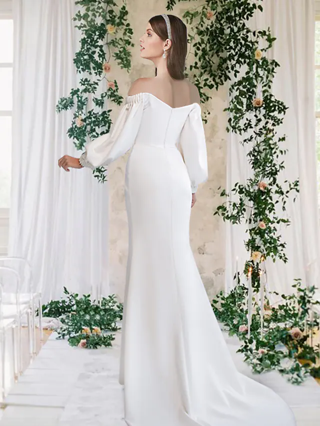 Full-length view of an elegant white off-shoulder bridal gown.