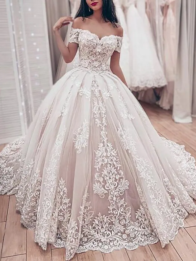 Close-up of intricate lace and applique details on an off-shoulder wedding dress.