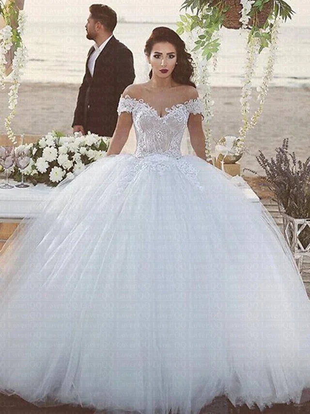 Front view of an elegant off-shoulder lace and tulle ball gown wedding dress.