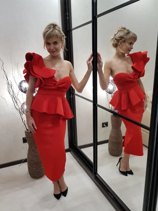 Back view of a woman in a one-shoulder ruffled tea-length cocktail dress.