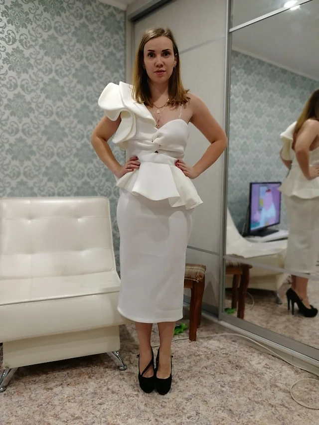 Side profile of a woman showcasing a one-shoulder ruffled tea-length dress.