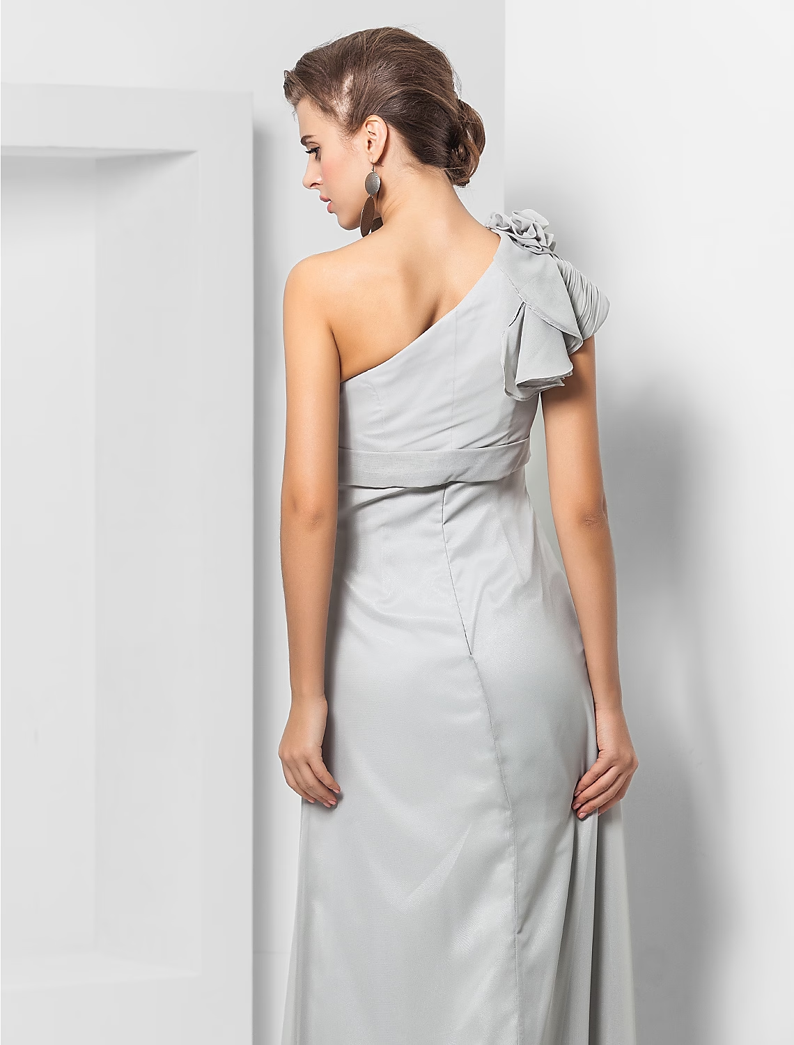 Woman posing in a sophisticated one-shoulder wedding guest dress.