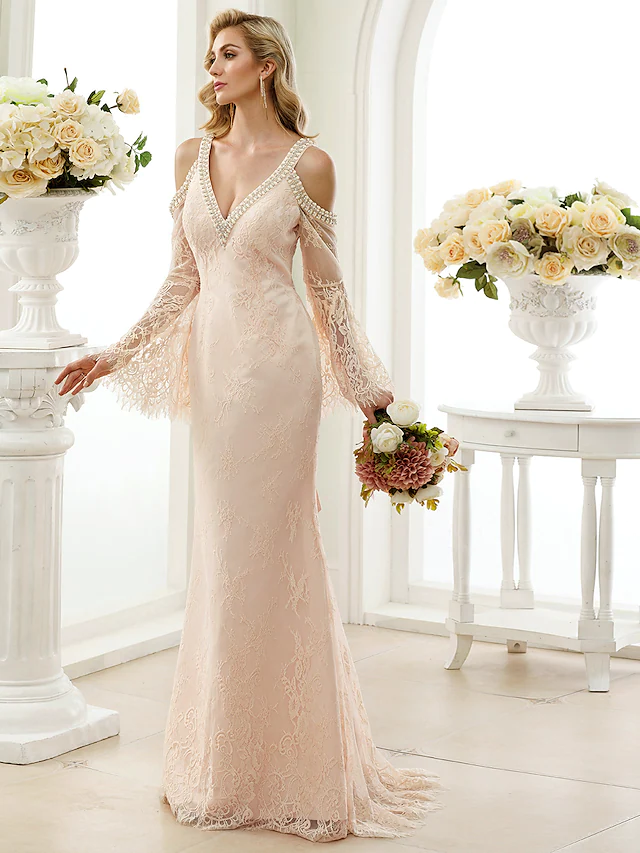 Elegant white wedding dress with plunging neckline and sheer long lace sleeves.