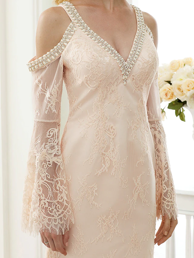 White wedding dress with plunging neckline, long sleeves, and intricate lace.