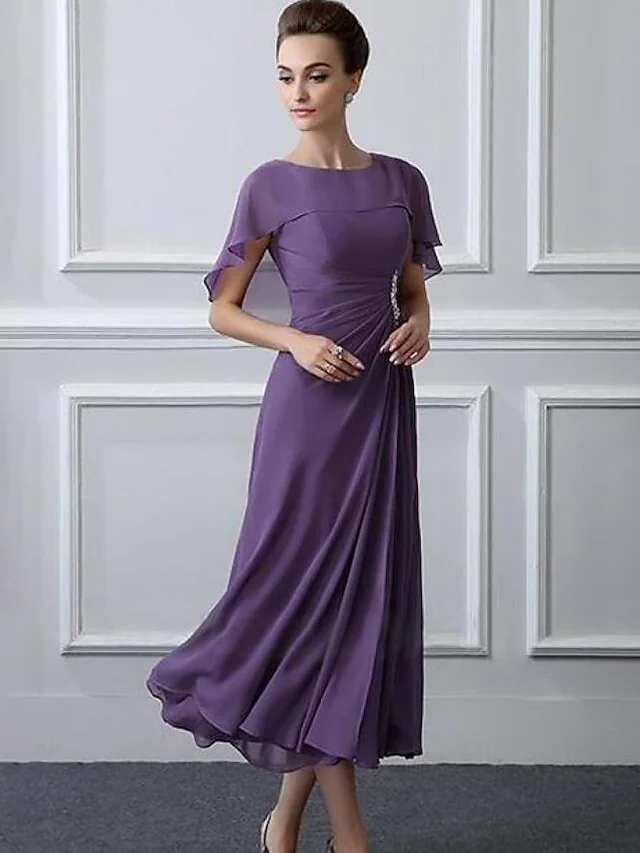 Close-up of the dress bodice, featuring the bateau neck and crystal brooch.