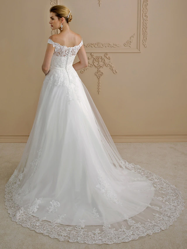Back view of a plus size off-shoulder ball gown wedding dress showing lace details and buttons.