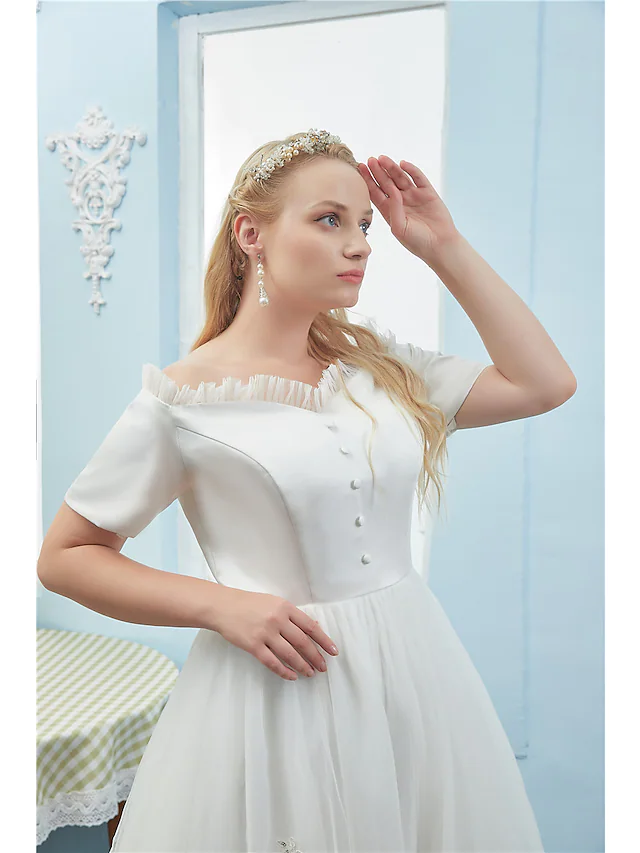 Detail of the tea-length tulle skirt with button accents on the elegant dress.