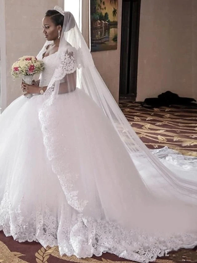 Full view of the elegant plus size V-neck ball gown wedding dress with lace appliques and cathedral train.