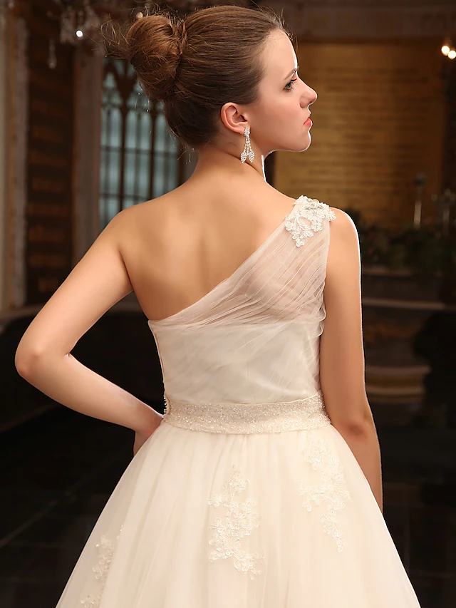Detailed view of the tulle skirt and court train of the wedding dress.