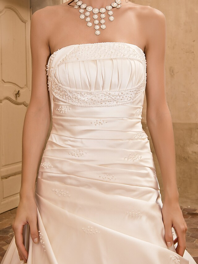 Bride posing in an elegant strapless A-line wedding dress.