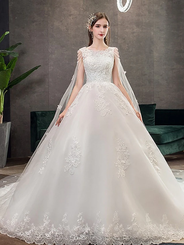 Front view of an elegant white princess ball gown wedding dress with a jewel neck and lace appliques.