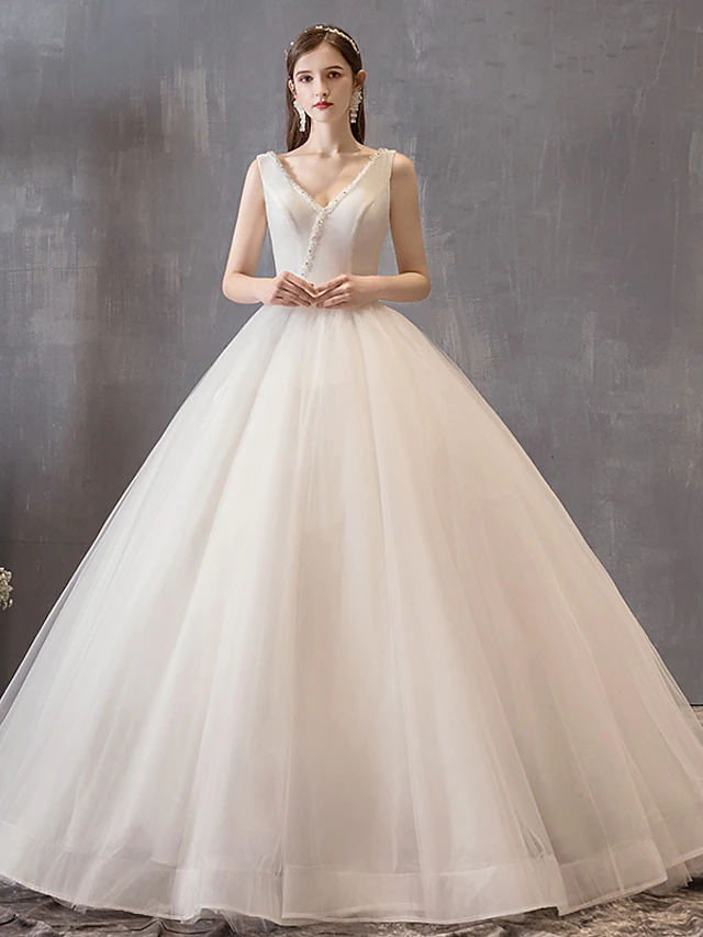 Elegant white princess ball gown wedding dress with V-neck, beading, and bow detail.