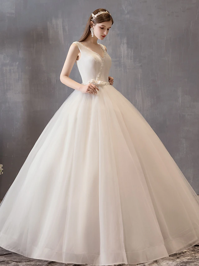 Close-up of the V-neckline and intricate beading on the white satin and tulle wedding dress.