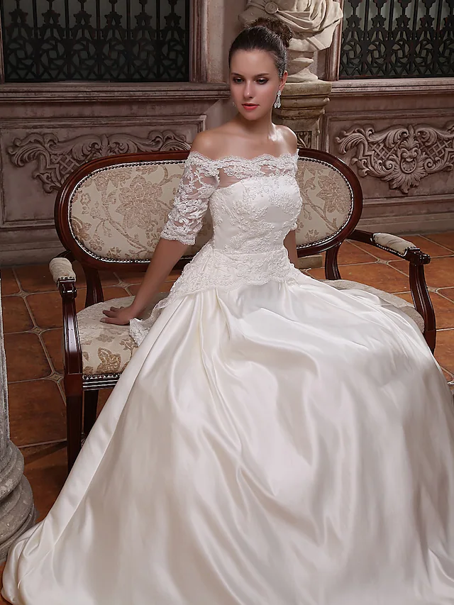 Close-up of the scalloped edge and off-shoulder neckline of the satin wedding dress.