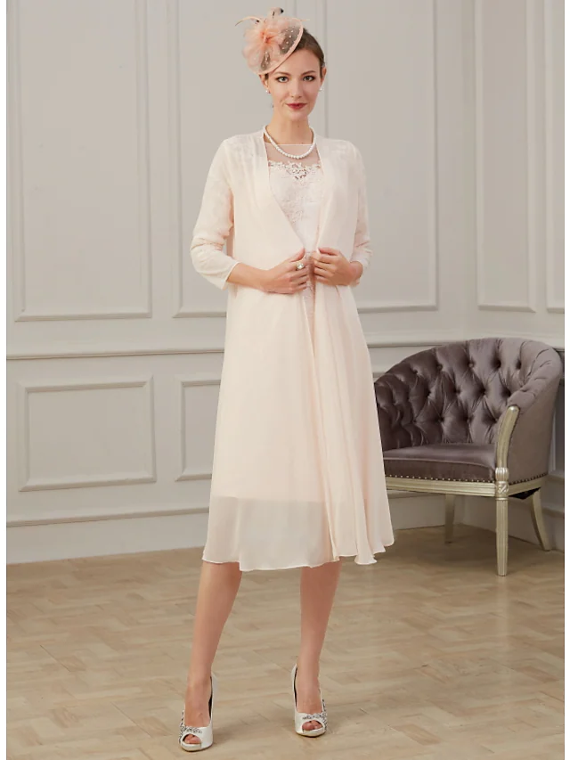 Elegant dark blue knee-length Mother of the Bride dress with jewel neck and long sleeves.