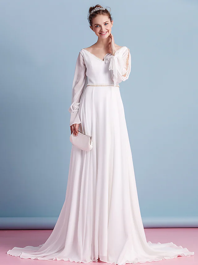 Bride walking in a long sleeve chiffon wedding dress with a court train.
