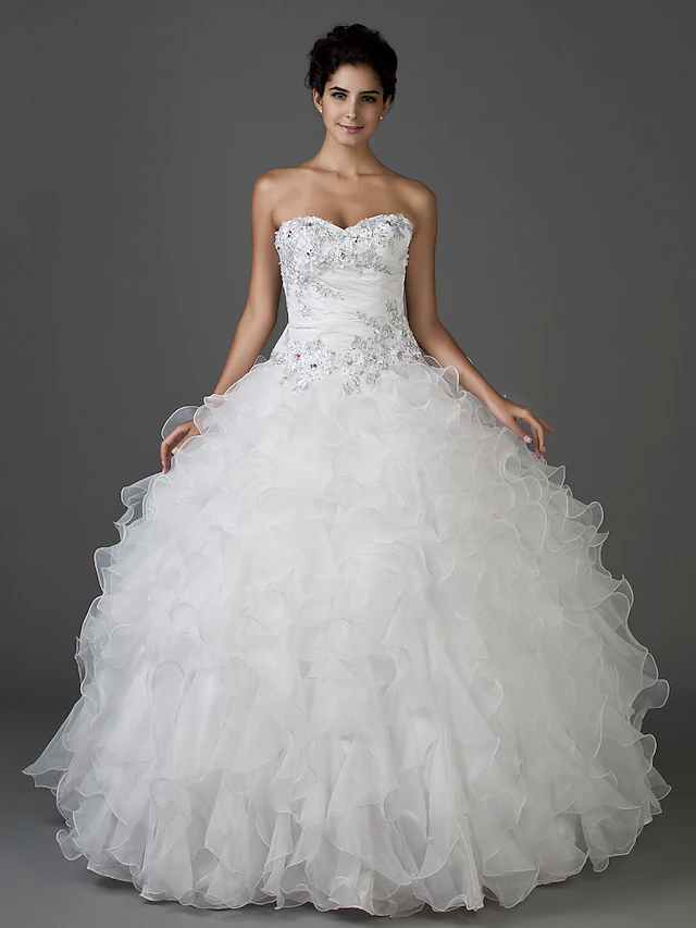 Full view of a sparkling white ball gown wedding dress with a sweetheart strapless neckline.