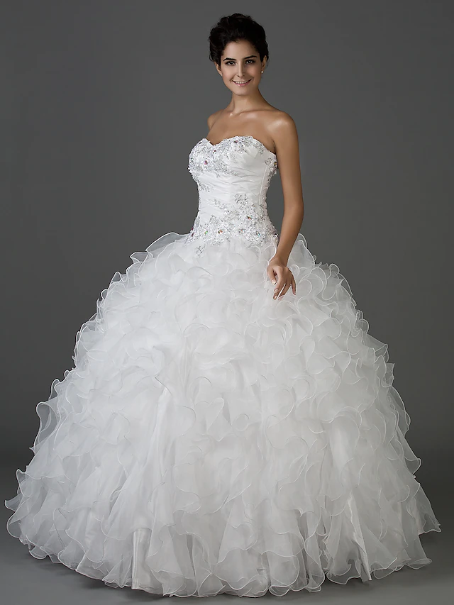 Side view of the voluminous, floor-length skirt of the sparkling bridal dress.