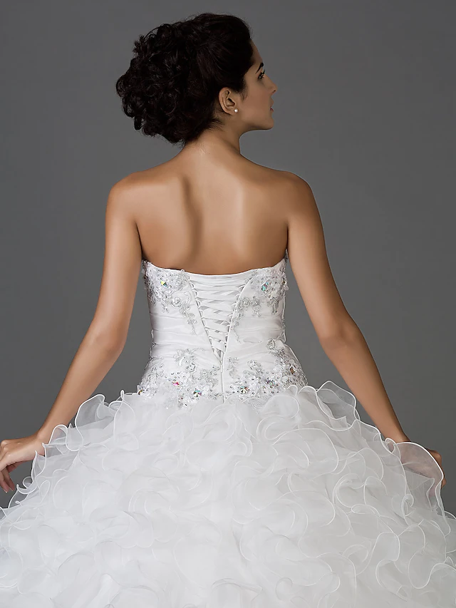 Bride posing gracefully in the white sweetheart strapless ball gown.