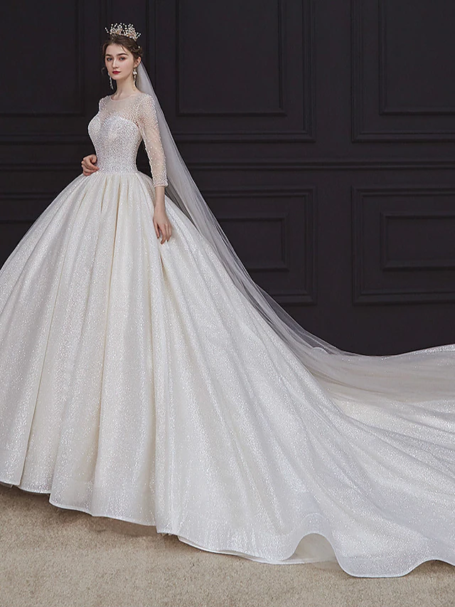 Elegant princess ball gown wedding dress with jewel neck and long sleeves.