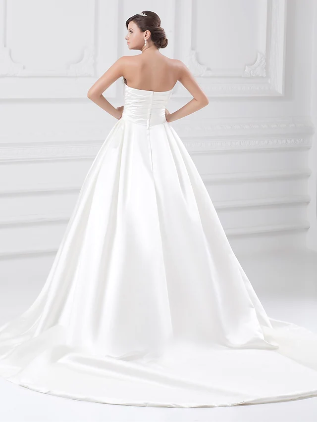 Plus size bride in a strapless satin ball gown wedding dress with ruched details.