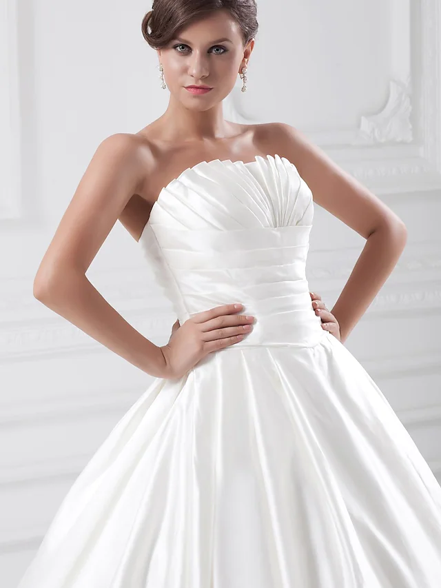 Close-up of the ruched draping on a strapless satin wedding dress.