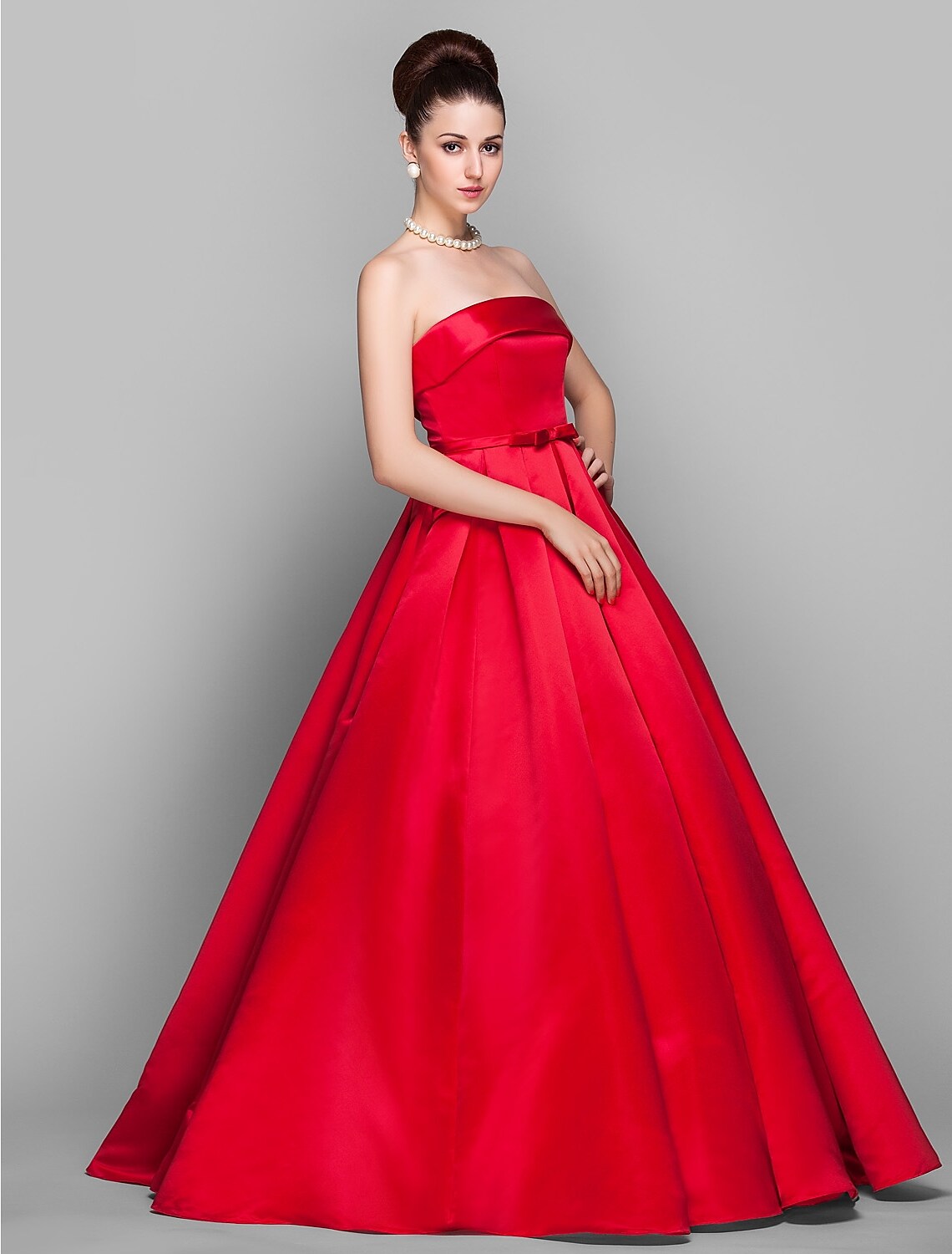 Full view of an elegant strapless blush pink ball gown with bow accents.