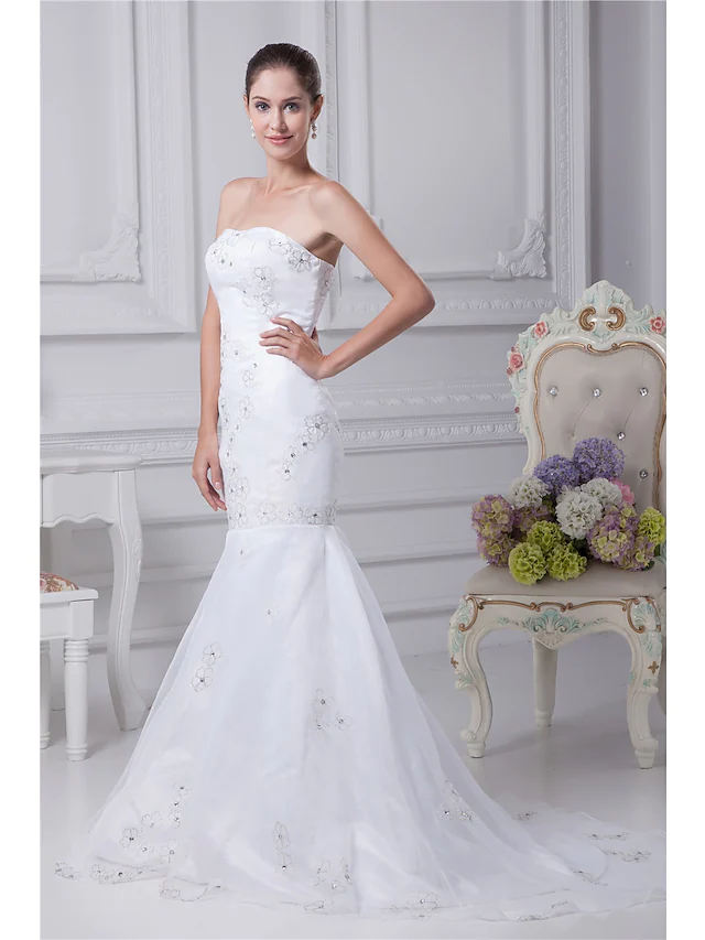 Back view of a strapless wedding gown, showcasing the chapel train and delicate embellishments.