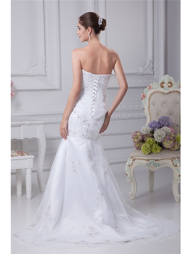 Close-up of the wedding dress bodice, highlighting the strapless neckline and detailed beading.