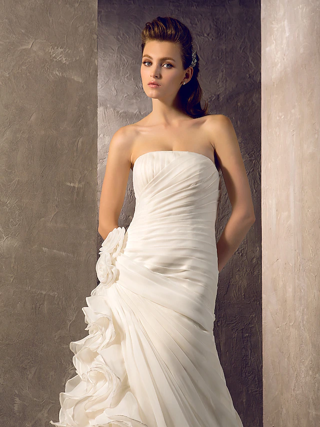 Bride posing gracefully in the strapless wedding dress, emphasizing its silhouette.