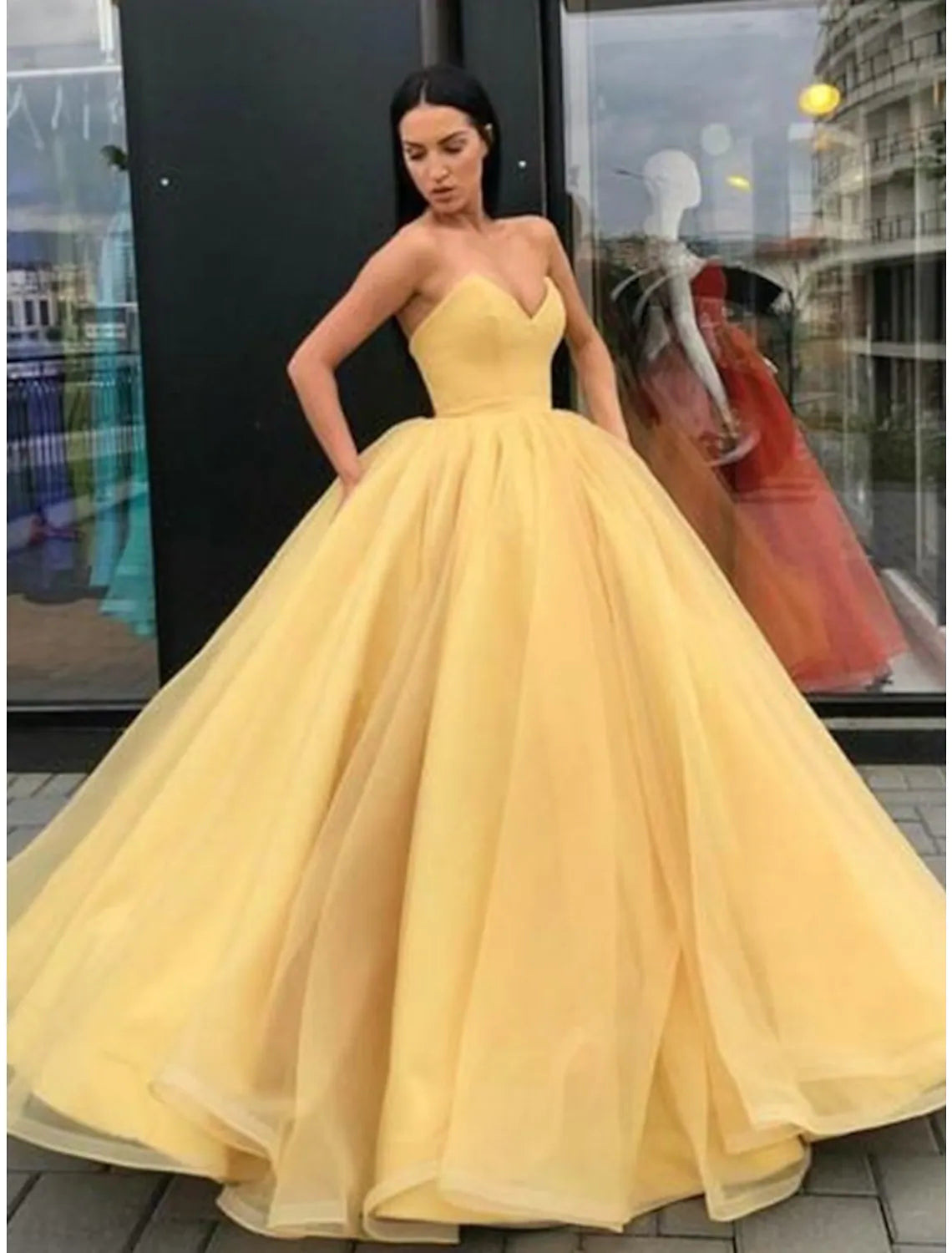Elegant strapless tulle ball gown with sleek pleats and a tiered skirt, viewed from the front.