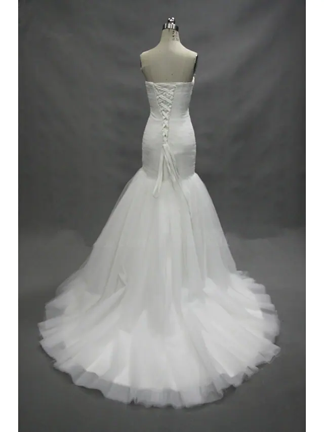Detailed view of the delicate tulle fabric and ruched texture on the white wedding dress.