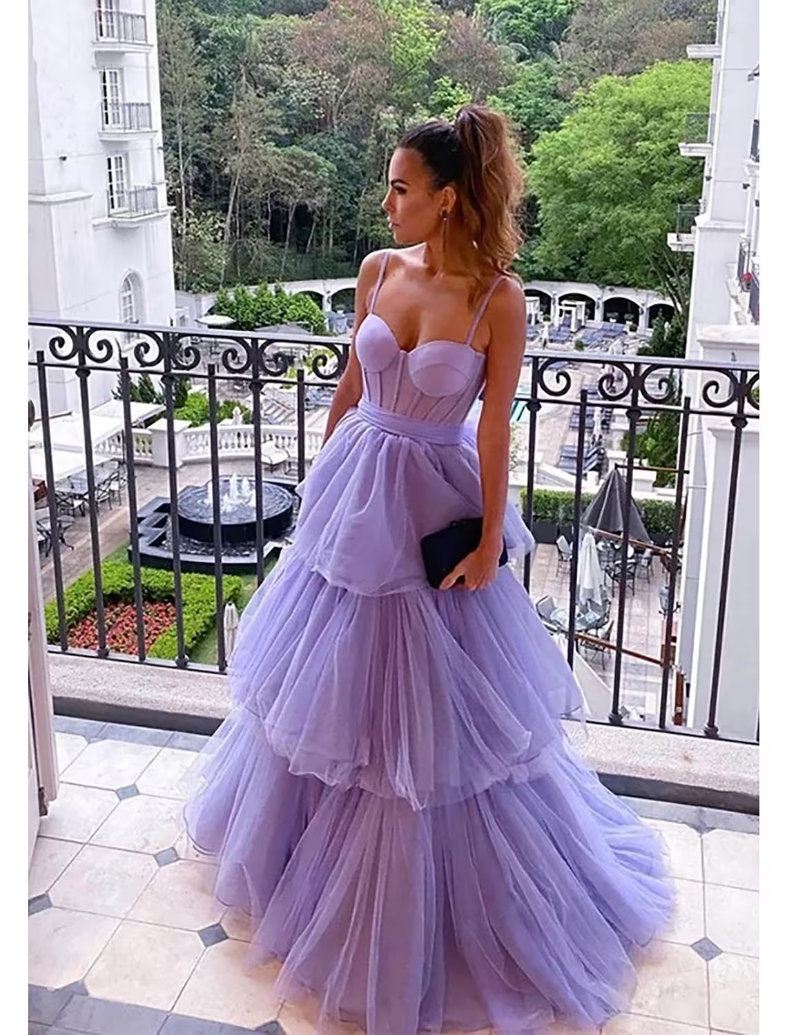 Model wearing a light pink tiered ball gown prom dress with a sweetheart neckline and floor-length tulle skirt.