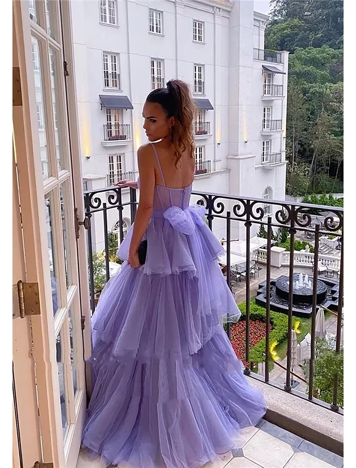 Back view of the light pink tiered ball gown prom dress, showcasing ruched details and pleats.