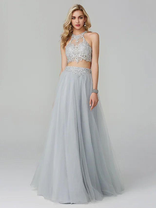 Model wearing a two-piece empire halter neck prom dress with lace appliques.