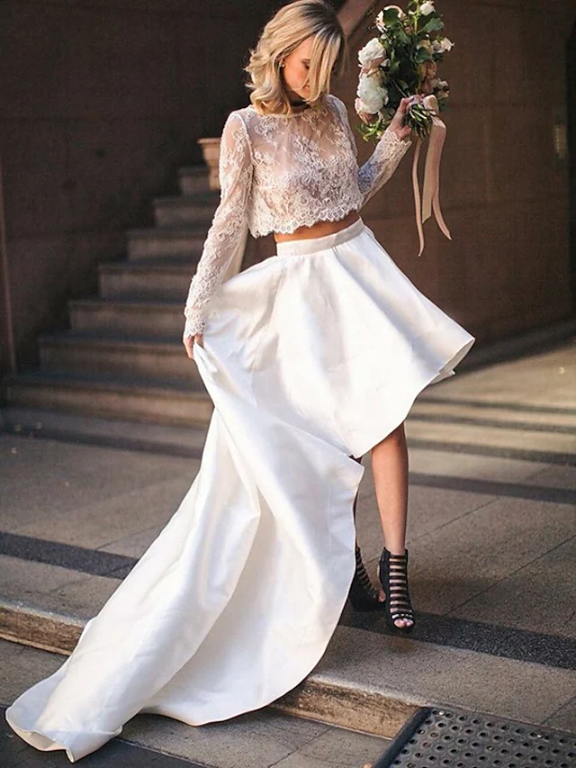 Model wearing an elegant two-piece jewel neck long sleeve lace and satin wedding dress with a court train.