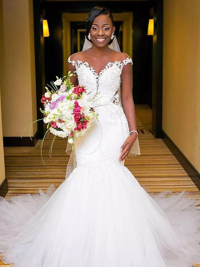 Front view of a white V-neck mermaid wedding dress with lace appliques and a chapel train.