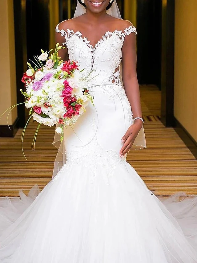 Side view of the white V-neck mermaid wedding dress, highlighting the lace details and train.