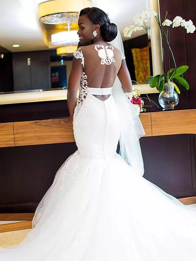 Close-up of the back of the white V-neck mermaid wedding dress, showing the backless design and appliques.