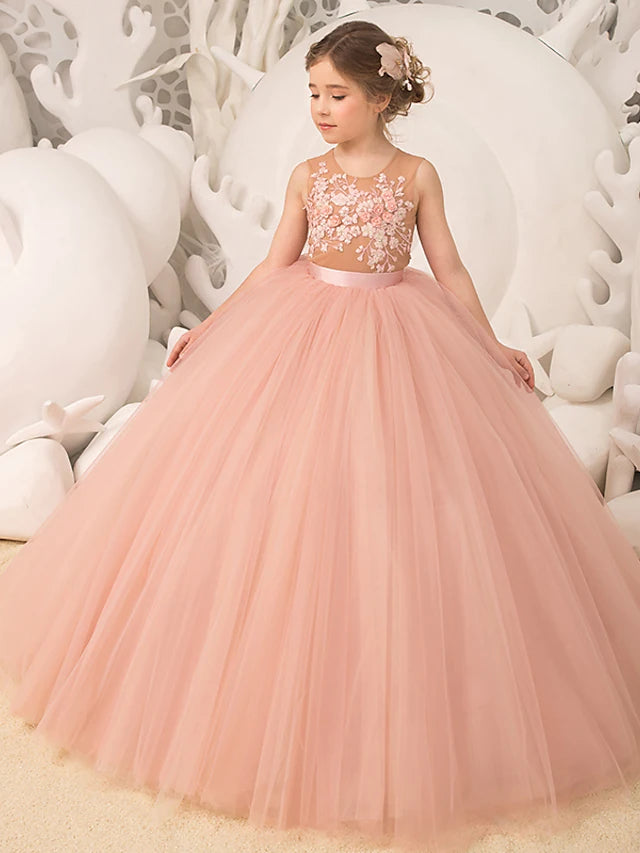 Flower girl in a white tulle dress with jewel neck and pleats, front view.